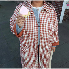 Person wearing a red and white checkered coat holding a pink ice cream.