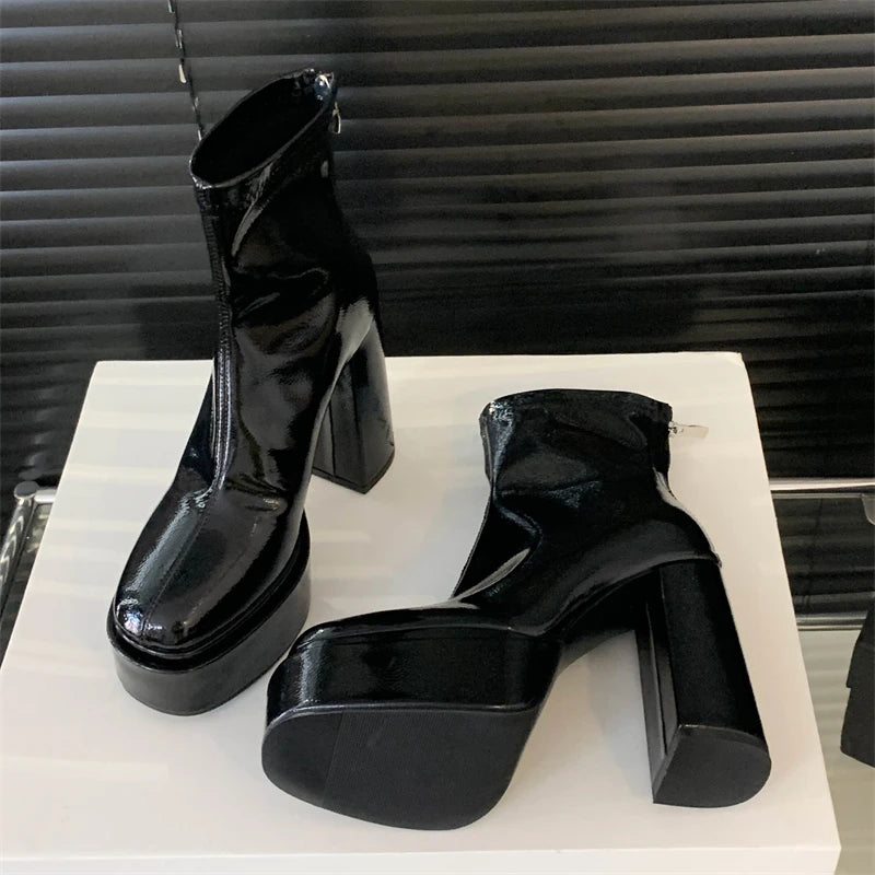 Black platform boots on a white platform with a black background