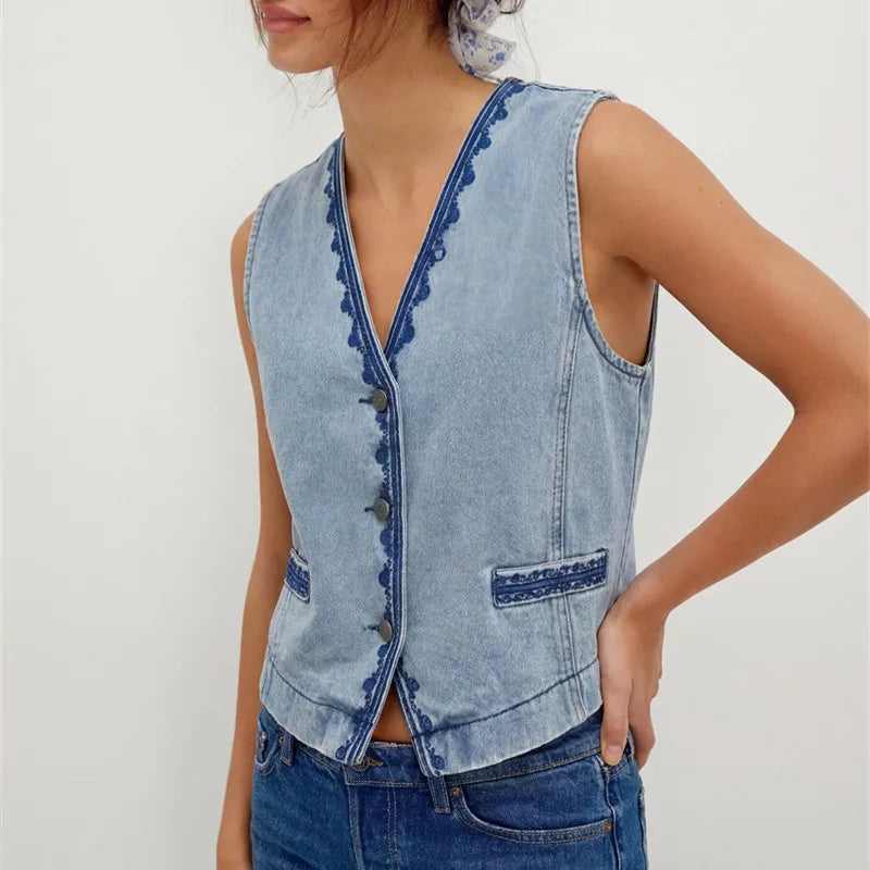 Detail of the embroidered trim on a light wash denim vest.
