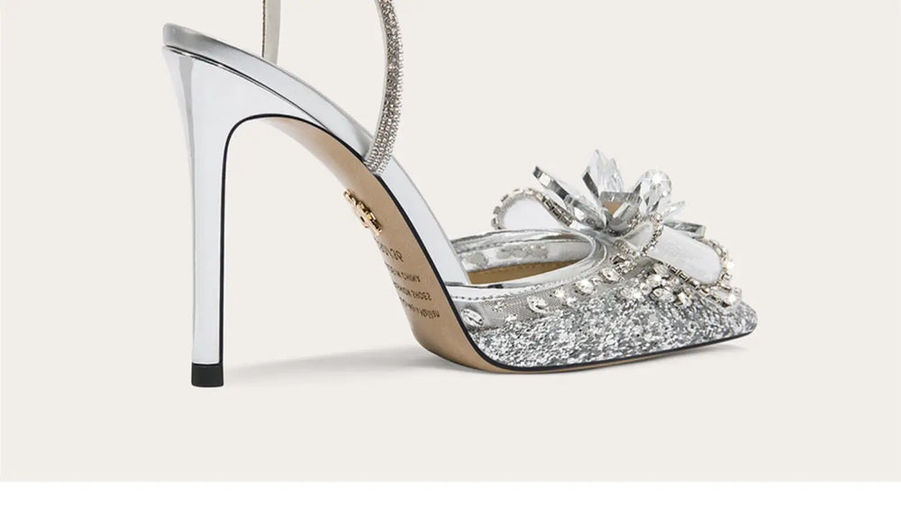 Sparkly high-heeled shoe with decorative bow on a light gray background