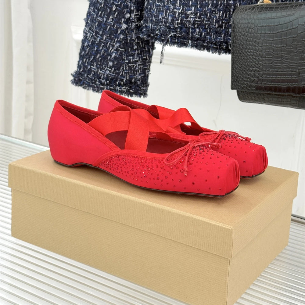 Red ballet flats on a beige shoe box with a blurred background