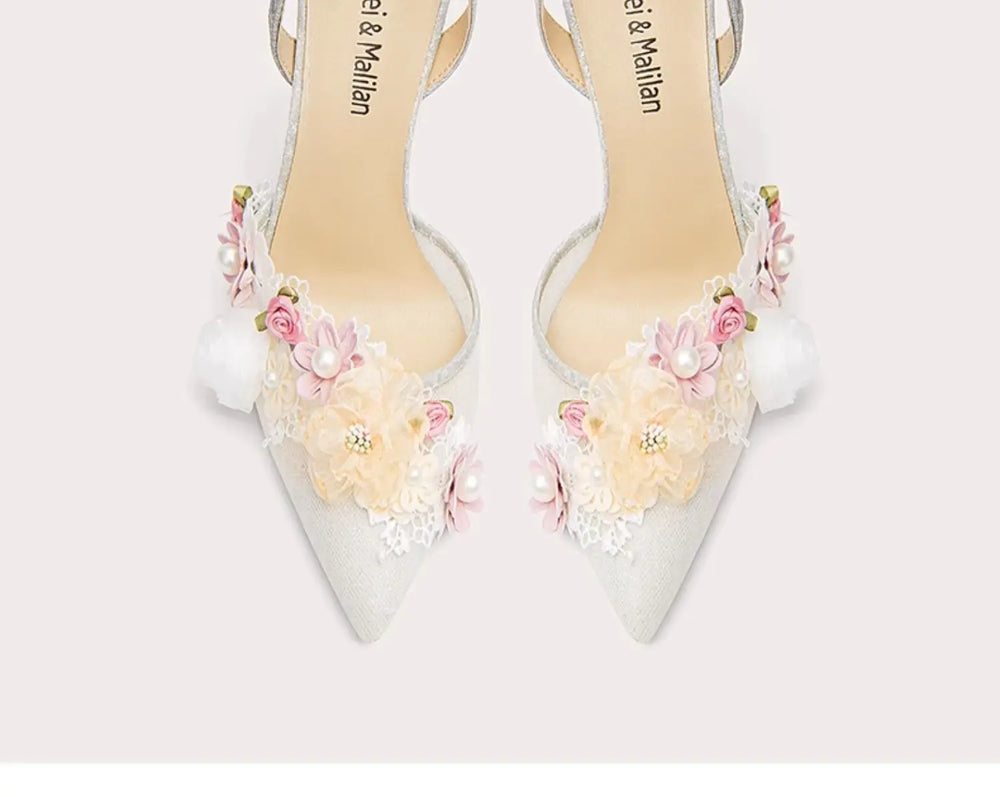 White high-heeled shoes with floral decorations on a white background