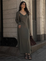 Woman in a long olive green dress standing on a street.