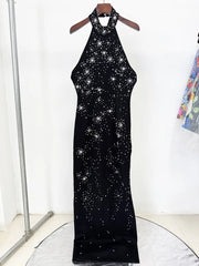Black dress with star pattern on a hanger against a white background