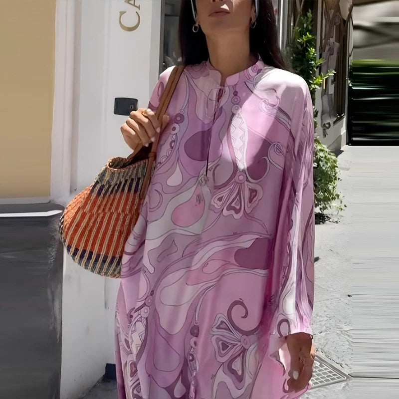 Woman wearing a pink patterned dress holding an orange bag on a street.