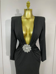 Black dress with a large brooch on a mannequin against a white background
