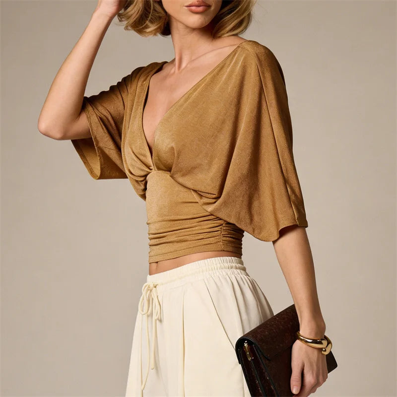 Woman wearing a brown top and white pants against a neutral background