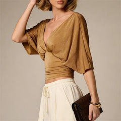 Woman wearing a brown top and white pants against a neutral background