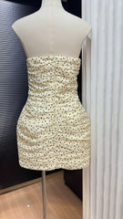 Beige strapless dress with black polka dots on a mannequin against a neutral background