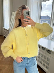 Person wearing a yellow cardigan and blue jeans taking a mirror selfie.