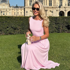 Woman in a pink dress sitting on grass with a historic building in the background