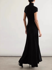 Person wearing a black dress with a plain background