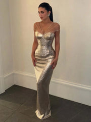 Woman wearing a silver sequin dress against a plain wall.