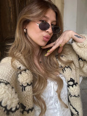 Woman wearing sunglasses and a patterned cardigan indoors