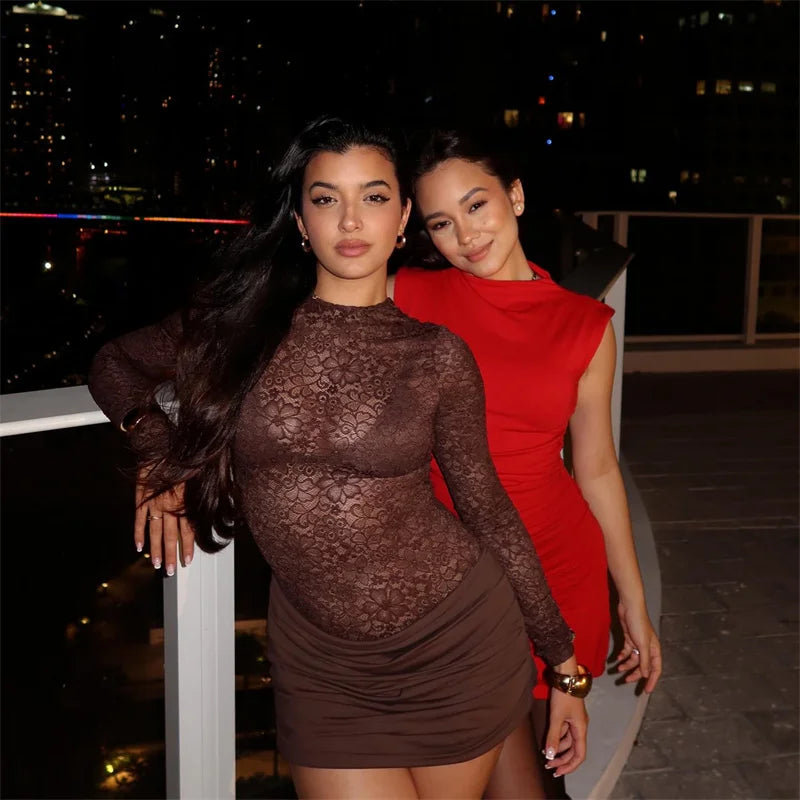 Two women posing together at night with a cityscape background