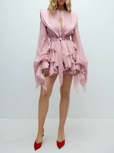 Pink ruffled dress worn by a person on a white background