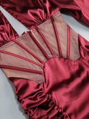 Red satin garment with sheer lace detailing on a light gray background