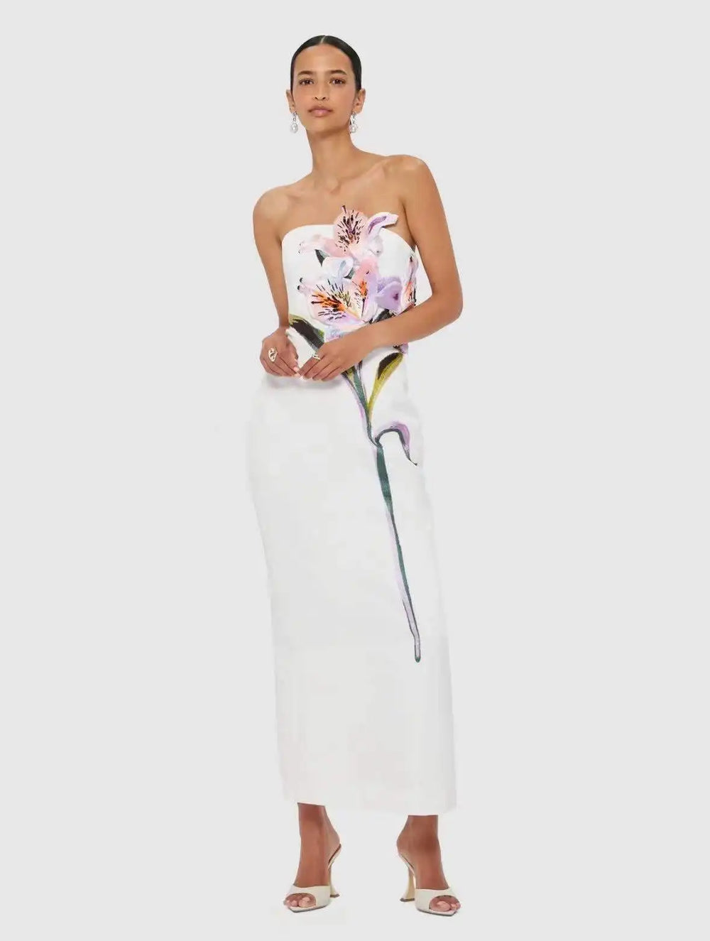 Model wearing a strapless column maxi dress with floral appliqué.