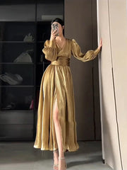 Woman wearing a gold dress with a slit, standing in a room.