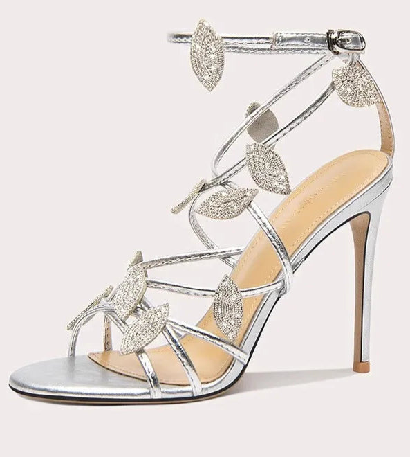 Silver high-heeled sandal with decorative straps on a white background