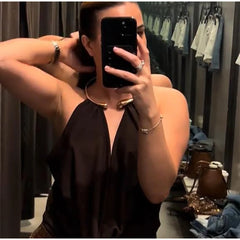 Woman taking a mirror selfie wearing a black sleeveless top in a clothing store.