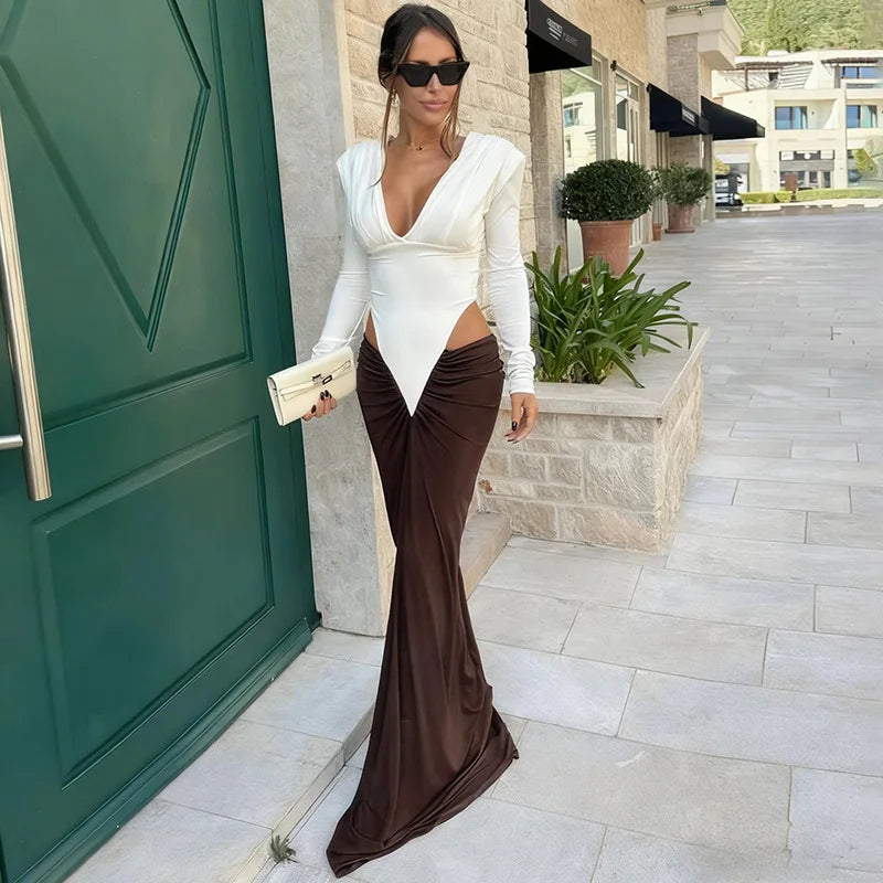 Woman in a white top and brown pants standing in front of a green door.