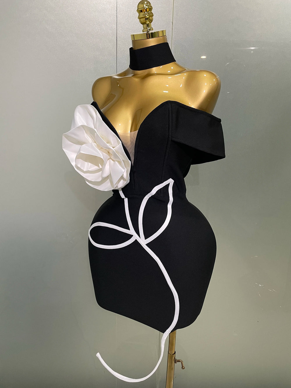 Black dress with white floral design on a mannequin against a plain background