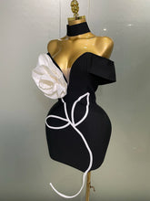 Black dress with white floral design on a mannequin against a plain background