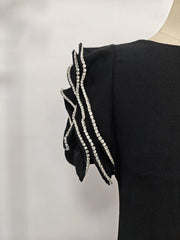 Black dress with decorative sleeves on a mannequin against a light background