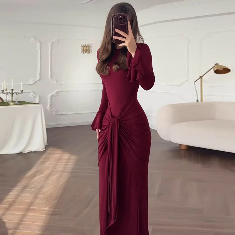 Person wearing a burgundy dress in an elegant room with a white sofa and table.
