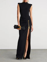Black evening gown with a high slit and gold belt on a plain background