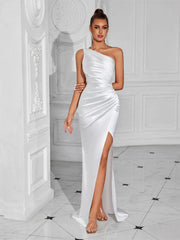 Woman wearing a white one-shoulder dress with a high slit in an elegant interior setting.