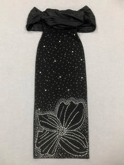 Black off-shoulder dress with floral embellishments on a light gray background