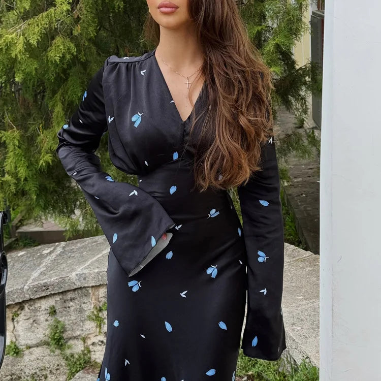 Woman wearing a black dress with blue patterns outdoors