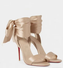 Pair of champagne satin stiletto heels with large bow ankle straps