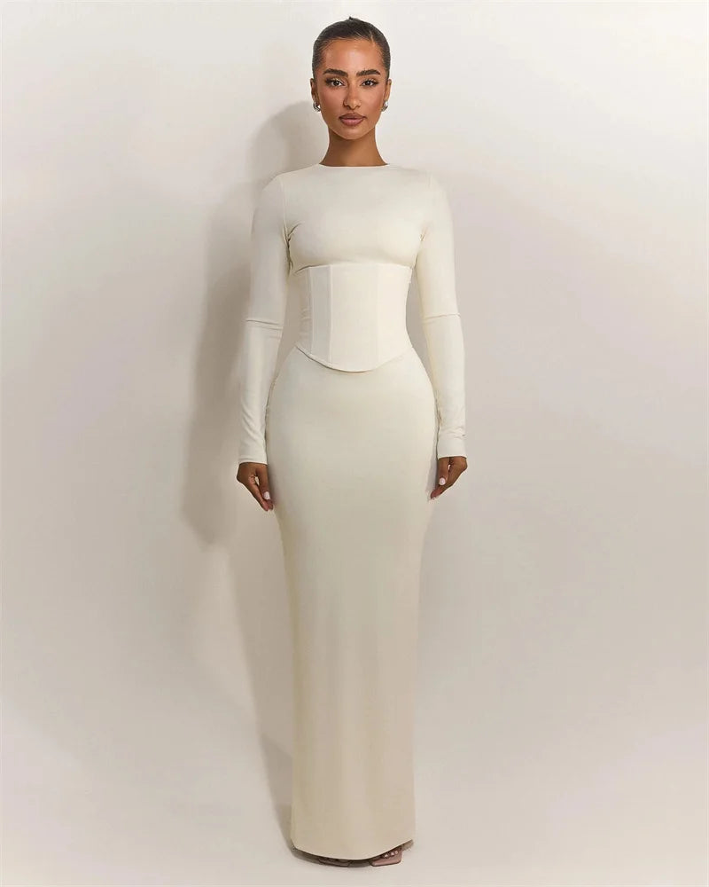 Woman wearing a white long-sleeve gown against a plain background