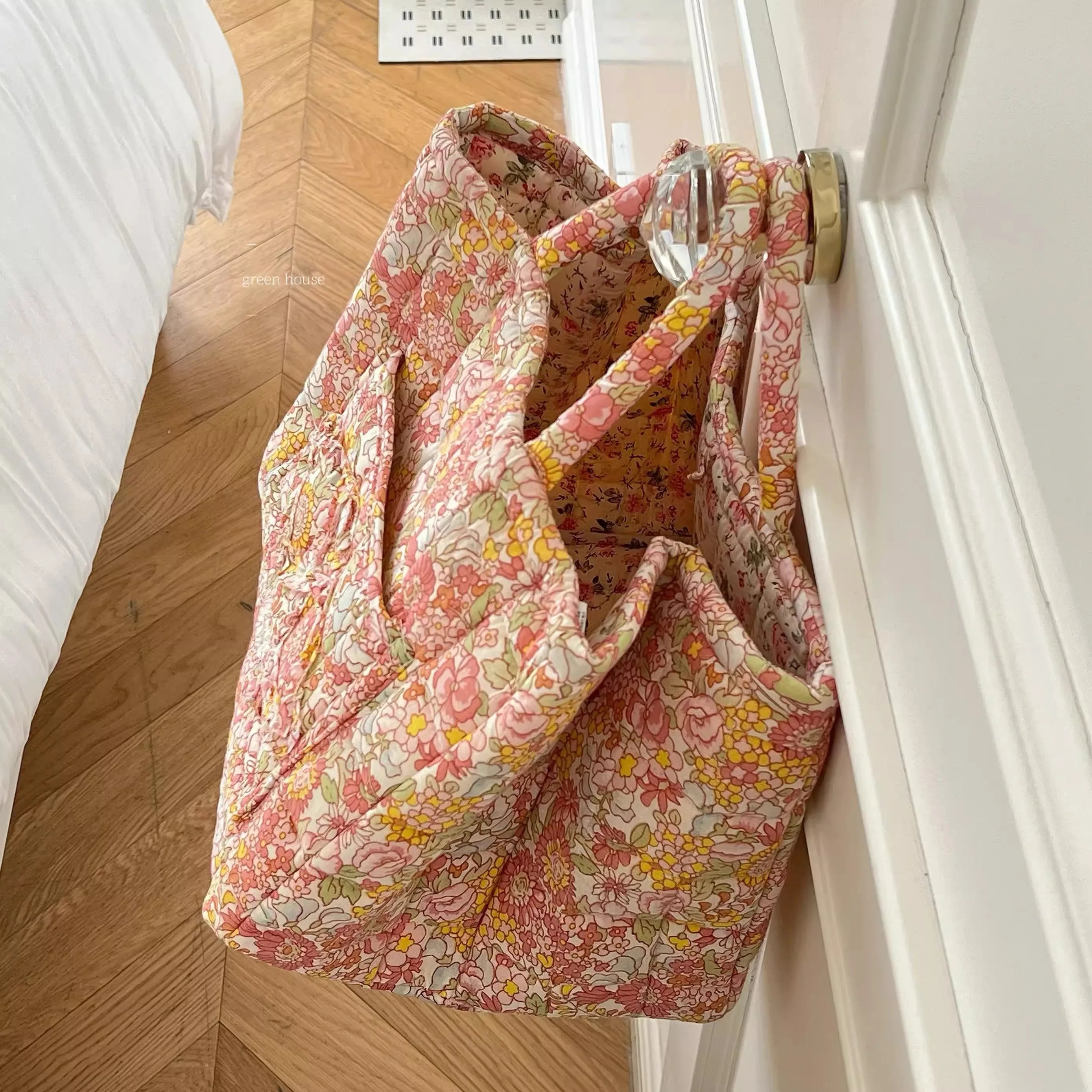 Floral-patterned bag hanging on a door handle.