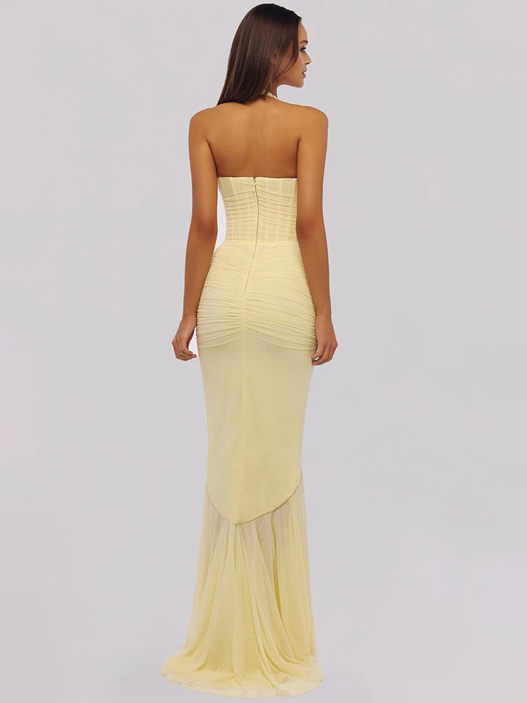 Woman wearing a strapless yellow evening gown on a plain background