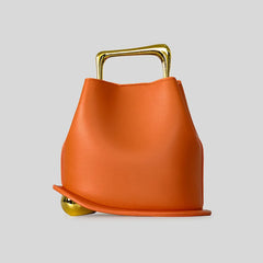 Orange handbag with gold handle and feet on a light gray background