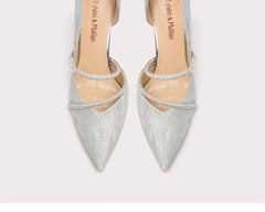 Pair of silver pointed-toe high heels with thin straps on a light gray background
