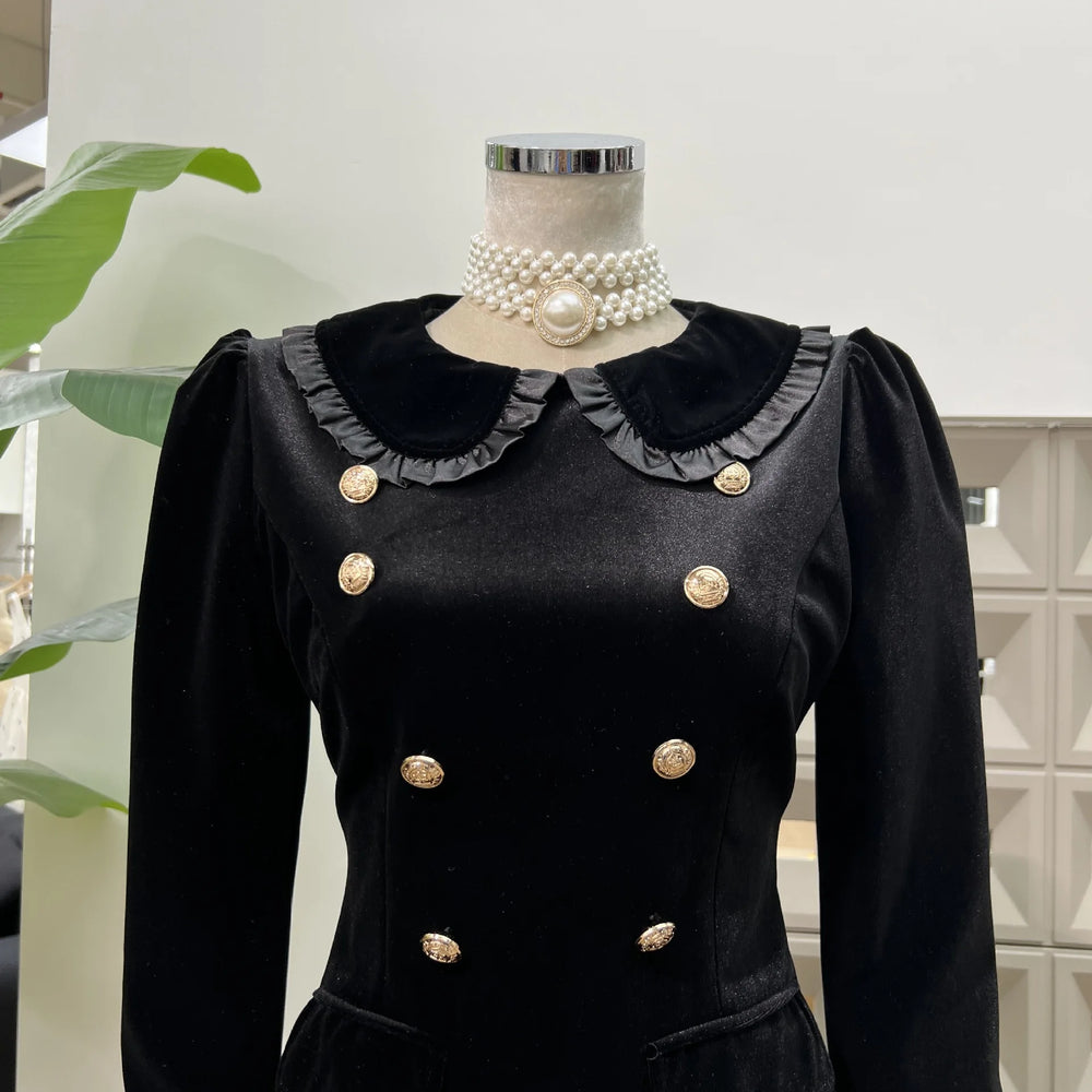 Black dress with gold buttons on a mannequin against a light background