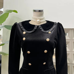 Black dress with gold buttons on a mannequin against a light background