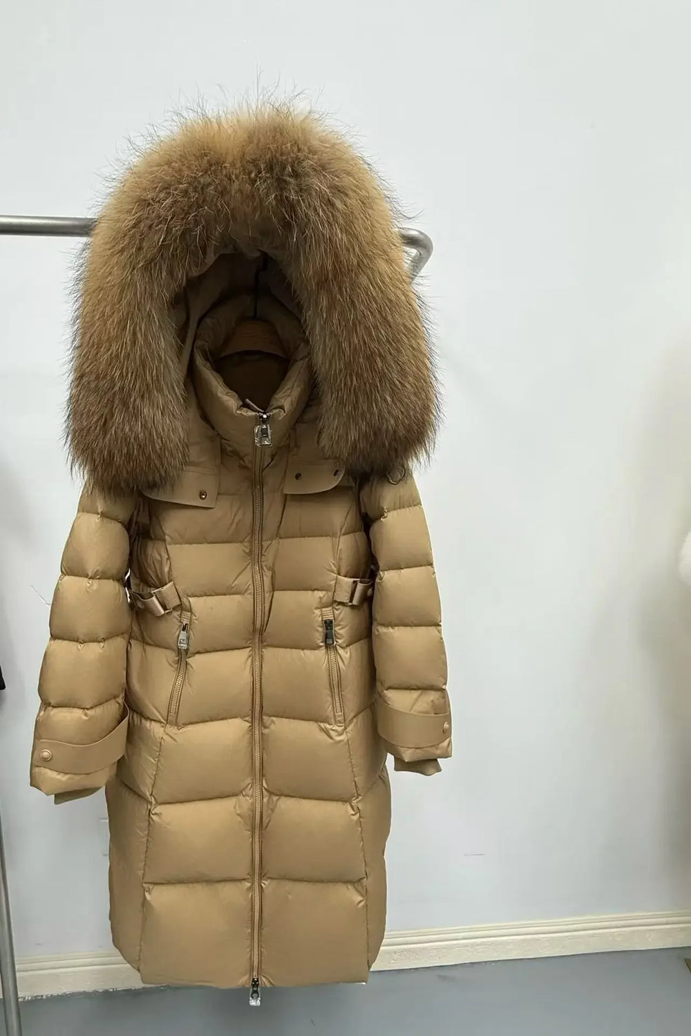 Beige puffer coat with a large fur hood on a white background