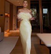 Woman in a white evening gown with feathered top in an indoor setting