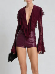 Person wearing a burgundy outfit with a deep neckline and high-waisted shorts on a light gray background