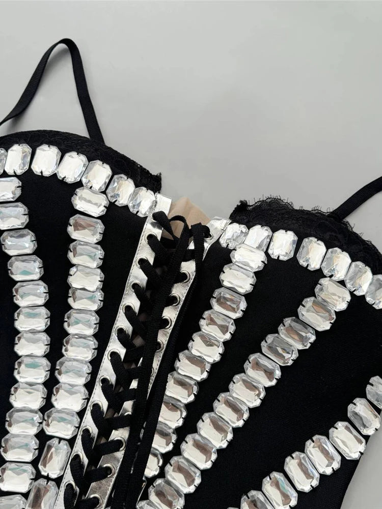 Black strappy top with silver embellishments on a gray background