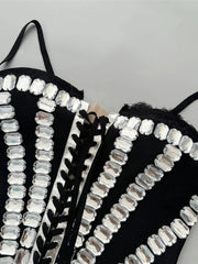 Black strappy top with silver embellishments on a gray background
