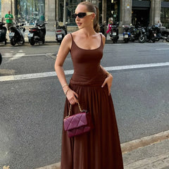 Woman in a brown dress holding a purple handbag on a city street.