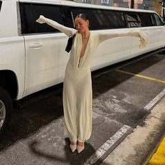 Woman in a long, light-colored dress standing in front of a white limousine.