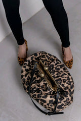 Leopard print handbag with gold clasp on a light gray floor.